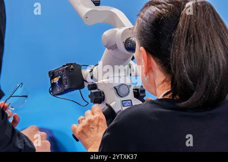 Una donna guarda nel binocolo di un microscopio dentale Foto Stock