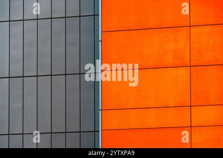 Edificio moderno con pannelli in grassetto arancione e pareti in metallo grigio a contrasto Foto Stock
