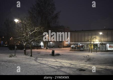 La città di Varkaus, Finlandia, con case, illuminazione stradale, negozi, negozi, parcheggi, le auto si stagliano nella neve bianca. Foto Stock