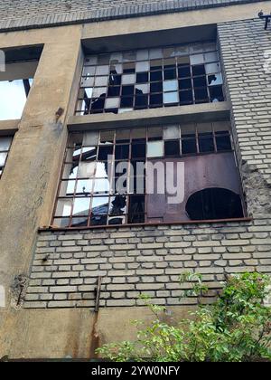 Edificio rustico abbandonato con finestre rotte e vegetazione sovrastata Foto Stock
