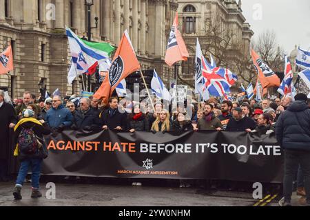 Londra, Regno Unito. 8 dicembre 2024. I manifestanti marciano con uno striscione che recita "agire contro l'odio prima che sia troppo tardi" durante la manifestazione a Whitehall. Migliaia di persone hanno marciato nel centro di Londra contro l'antisemitismo e a sostegno di Israele mentre Israele continua i suoi attacchi a Gaza. Credito: SOPA Images Limited/Alamy Live News Foto Stock