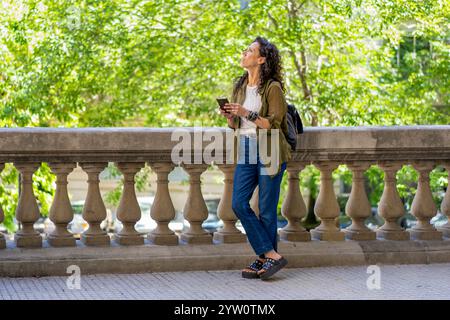 Utente su uno smartphone in un ambiente urbano vivace Foto Stock