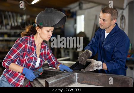 L'uomo allena la donna a collegare i binari di ferro con la saldatrice. Foto Stock