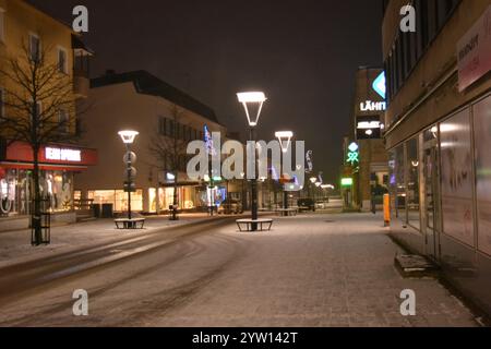 La città di Varkaus, Finlandia, con case, illuminazione stradale, negozi, negozi, parcheggi, le auto si stagliano nella neve bianca. Foto Stock