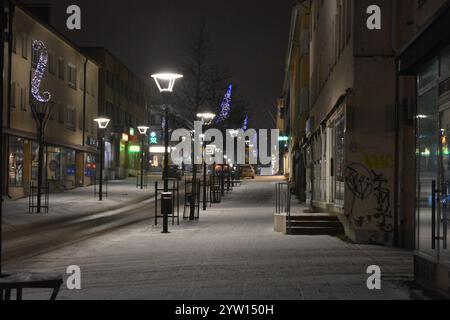 La città di Varkaus, Finlandia, con case, illuminazione stradale, negozi, negozi, parcheggi, le auto si stagliano nella neve bianca. Foto Stock