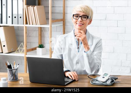 Trattamento accessibile. Donna sorridente dottore seduto al tavolo Foto Stock