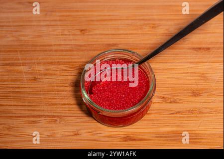 capriolo rosso e cucchiaio in un vaso di vetro su un tagliere Foto Stock