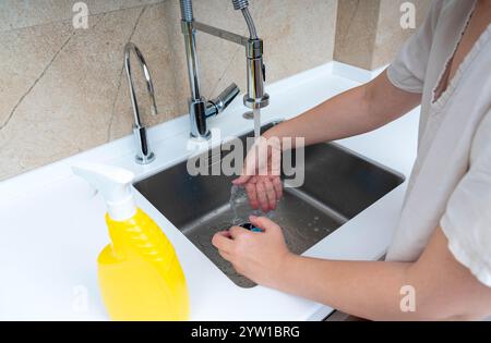 Lavaggio a mano con spugna e detergente in un moderno lavello da cucina dopo la pulizia. Foto Stock