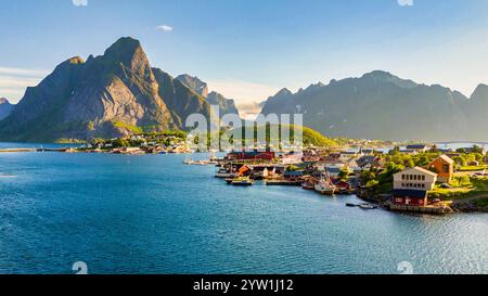 Esplora il pittoresco villaggio di Reine nelle Isole Norways Lofoten, dove montagne maestose e acque tranquille creano uno sfondo ideale per l'avventura Foto Stock