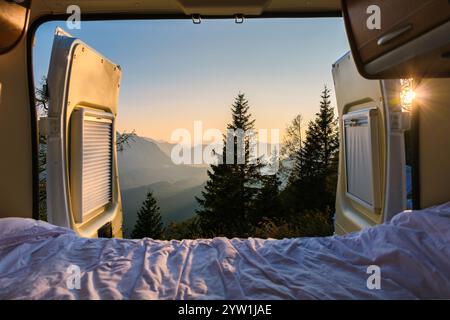 Una mattinata serena si dispiega mentre la luce del sole scorre attraverso le porte aperte di un camper, rivelando un panorama mozzafiato sulle Alpi austriache, Foto Stock