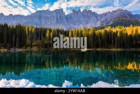 Le acque cristalline rispecchiano le maestose vette delle Dolomiti, circondate da lussureggianti foreste sempreverdi sotto un cielo vibrante. Lago Carezza o Karersee Do Foto Stock