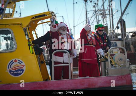 Richmond, Canada. 8 dicembre 2024. Un uomo vestito da Babbo Natale ondeggia alla gente da una barca a Steveston Fisherman's Wharf a Richmond, British Columbia, Canada, 8 dicembre 2024. L'evento Babbo Natale's Arrival by Boat si è tenuto qui domenica per dare il via alle festività natalizie. Crediti: Liang Sen/Xinhua/Alamy Live News Foto Stock