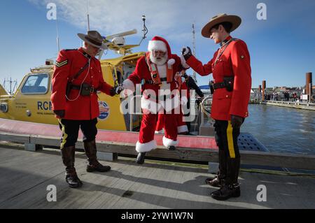 Richmond, Canada. 8 dicembre 2024. I membri della Royal Canadian Mounted Police assistono Babbo Natale mentre sbarca da una barca a Steveston Fisherman's Wharf a Richmond, British Columbia, Canada, 8 dicembre 2024. L'evento Babbo Natale's Arrival by Boat si è tenuto qui domenica per dare il via alle festività natalizie. Crediti: Liang Sen/Xinhua/Alamy Live News Foto Stock