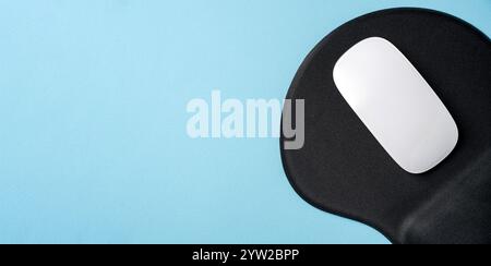 Vista dall'alto del mouse bianco moderno sul tappetino nero sul tavolo blu Foto Stock
