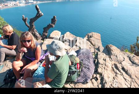 Sestri Levante, Italia - 10 novembre 2024. Escursioni in montagna. Persone in abiti sportivi con zaini, che riposano sulla roccia. Foto Stock