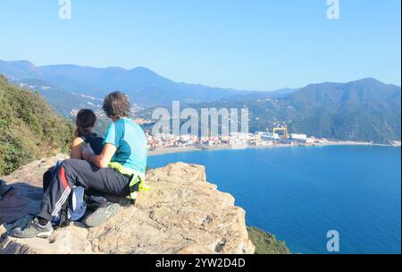 Sestri Levante, Italia - 10 novembre 2024. Escursioni in montagna. Persone in abiti sportivi con zaini, che riposano sulla roccia. Foto Stock