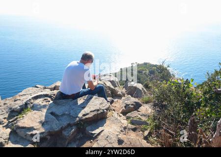 Sestri Levante, Italia - 10 novembre 2024. Escursioni in montagna. Persone in abiti sportivi con zaini, che riposano sulla roccia. Foto Stock