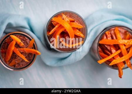 Moka mouse o mousse al cioccolato con buccia d'arancia candita e petali di mandorla in bicchieri di vetro su sfondo blu con un tovagliolo blu cielo. Foto di alta qualità Foto Stock