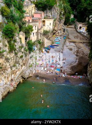 Gli amanti del sole si godranno la pittoresca spiaggia nascosta sulla Costiera Amalfitana, circondata da scogliere rocciose ed edifici affascinanti. Fiordo di Furore, il Furore bea Foto Stock