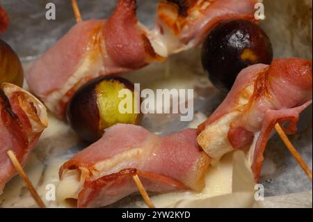 Gli spuntini con pancetta ripieni di formaggio e fichi succosi creano un'esperienza appetitosa in occasione di un evento sociale. Foto Stock