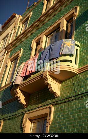 La colorata lavanderia si asciuga sul balcone di un edificio piastrellato verde sotto un cielo limpido, il Portogallo Foto Stock