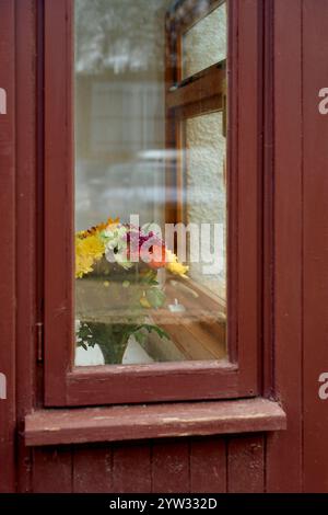 Un bouquet colorato di fiori freschi in un vaso seduto su un davanzale dietro una finestra incorniciata in legno, la Scozia Foto Stock