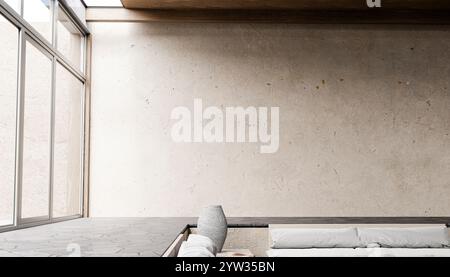 Illustrazione di un interno minimalista con un letto basso, lenzuola bianche e grandi finestre da pavimento a soffitto che lasciano entrare luce naturale. Foto Stock