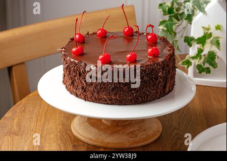 una torta intera al cioccolato decorata con ciliegie Foto Stock
