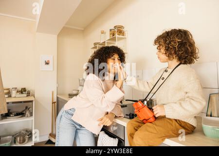 Un momento di gioia condiviso tra una madre e suo figlio in cucina. Condividono un cinque alto, evidenziando il legame e la felicità nelle loro relazioni Foto Stock