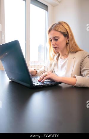 Donna professionista che lavora su un notebook in un ufficio moderno. Verticale Foto Stock