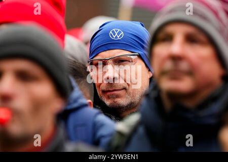 Wolfsburg, Germania. 9 dicembre 2024. Un dipendente indossa un berretto con il logo Volkswagen all'esterno della sede centrale del produttore automobilistico Volkswagen a Wolfsburg durante uno sciopero di avvertimento IG Metall. Credito: Martin Meissner/AP POOL/dpa/Alamy Live News Foto Stock