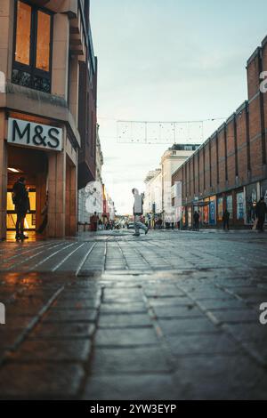 Uomo che attraversa Queen's Street il giorno invernale a Exeter Foto Stock