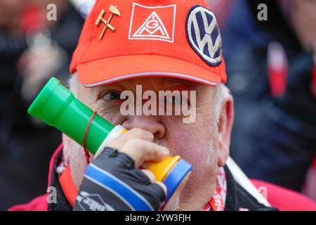 Wolfsburg, Germania. 9 dicembre 2024. Un dipendente soffia un clacson durante uno sciopero di avvertimento IG Metall fuori dalla sede centrale della casa automobilistica Volkswagen a Wolfsburg. Credito: Martin Meissner/AP POOL/dpa/Alamy Live News Foto Stock