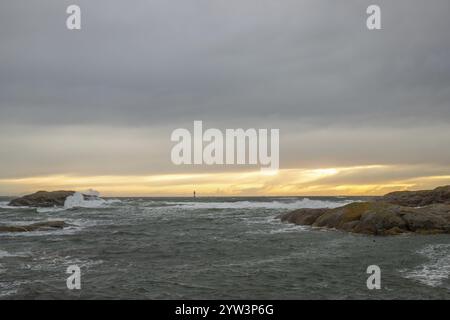 Un faro si trova nella tempesta. Mare selvaggio la sera. Tramonto su una costa con molte rocce nel Mare del Nord. Paesaggio marino in Svezia, Scandinavia Foto Stock