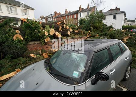 Danni a un veicolo nelle vicinanze dopo che un albero di cedro è caduto a Leamington Spa, dopo Storm Darragh, che ha portato un uomo ad essere precipitato in ospedale il sabato. La tempesta ha portato forti raffiche in molte parti del paese durante il fine settimana, con milioni di persone avvertite di rimanere al chiuso. Data immagine: Lunedì 9 dicembre 2024. Foto Stock