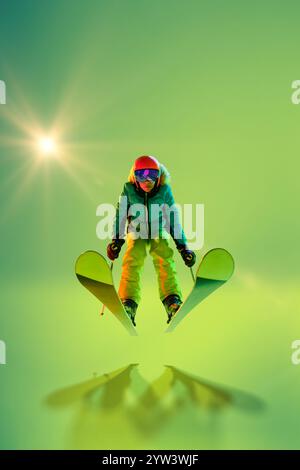 Sciatore che esegue un salto impressionante, congelato a mezz'aria in tonalità verde neon su sfondo studio. Movimento. Foto Stock