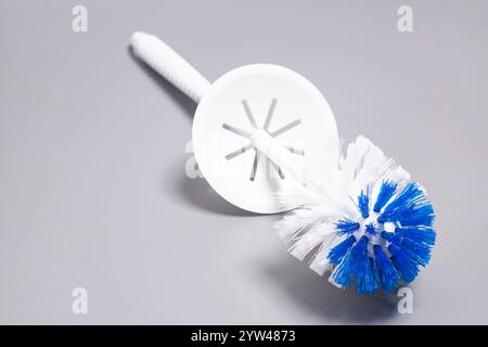 Mentre lo spazzolino del water è su sfondo grigio Foto Stock