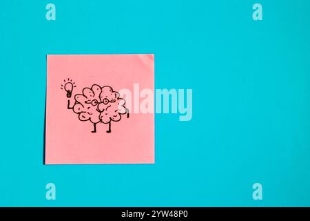 Carta appiccicosa rosa con cervello disegnato che regge una lampadina su sfondo blu, concetto di cervello e idee Foto Stock