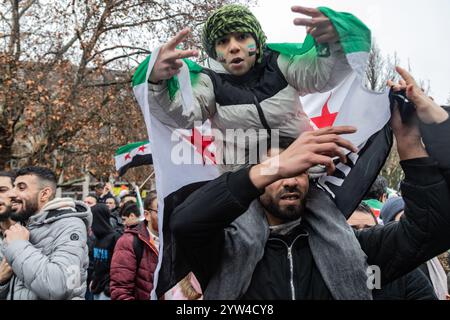 Un padre e un figlio partecipano alla festa. I siriani che vivono a Berlino celebrano la caduta del regime di Assad dopo una guerra civile dal 2011. Foto Stock