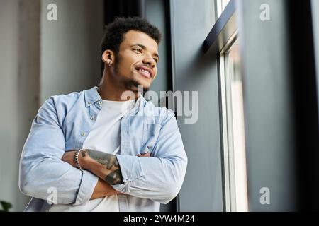 Un uomo affascinante riflette gioiosamente mentre si appoggia a una finestra in uno spazio contemporaneo. Foto Stock