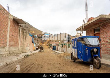 Lurin, Perù - 29 luglio 2023: Rural Street with TukTuk in a Dry Developing Neighborhood in the Mountains near Lima Foto Stock