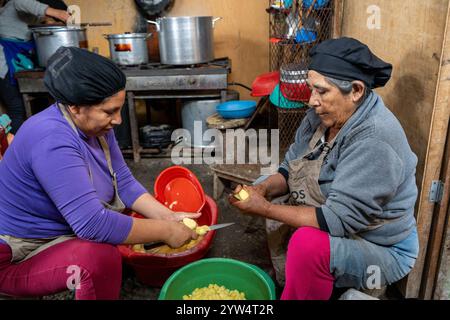 Lurin, Perù - 29 luglio 2023: Due donne lavano, tagliano e pelano le patate insieme in secchi in Modest Community Kitchen Foto Stock