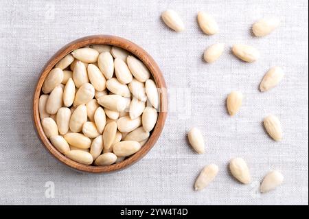 Mandorle cotte in una ciotola di legno su tessuto di lino. Mandorle sgusciate, trattate con acqua calda per rimuovere lo strato di semi e rivelare i semi. Foto Stock