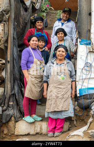 Lurin, Perù - 29 luglio 2023: Donne e uomini che lavorano in una cucina comunitaria posano sul set di scale anteriori Foto Stock