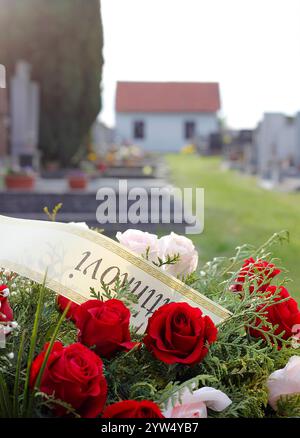 Primo piano di una fresca corona floreale fatta di rose sulla tomba dopo un funerale. Corona funebre con dedica in lingua ceca (dire a papà) Foto Stock