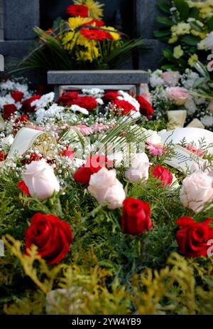 Primo piano di fresche corone floreali fatte di rose rosse e rosa sulla tomba dopo un funerale. Corone funebri in un cimitero della Repubblica Ceca. Foto Stock