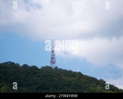 Array di antenne direzionali su una torre di comunicazione rossa e bianca contro il cielo. Foto Stock