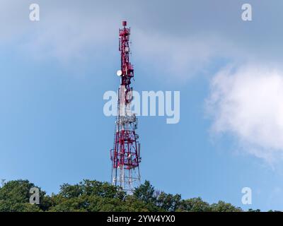 Array di antenne direzionali su una torre di comunicazione rossa e bianca contro il cielo. Foto Stock
