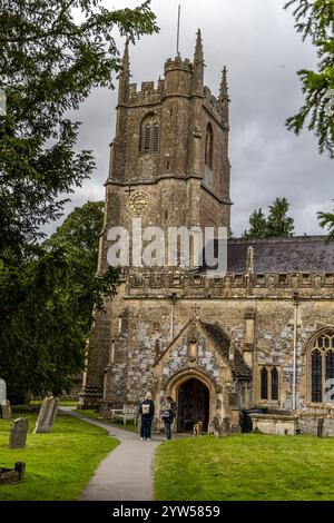 Avebury, Regno Unito - 25 agosto 2024: La chiesa di Avebury risale all'anno 1000 d.C. e si trova vicino ad Avebury Manor nel Wiltshire. una donna siede su una panchina, besi Foto Stock