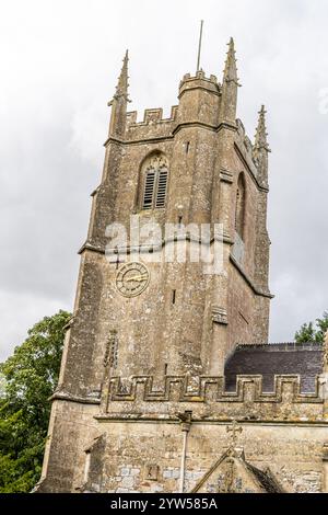 Avebury, Regno Unito - 25 agosto 2024: La chiesa di Avebury risale all'anno 1000 d.C. e si trova vicino ad Avebury Manor nel Wiltshire. una donna siede su una panchina, besi Foto Stock